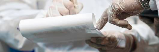 Two medical professionals' hands jotting down information on legal pad